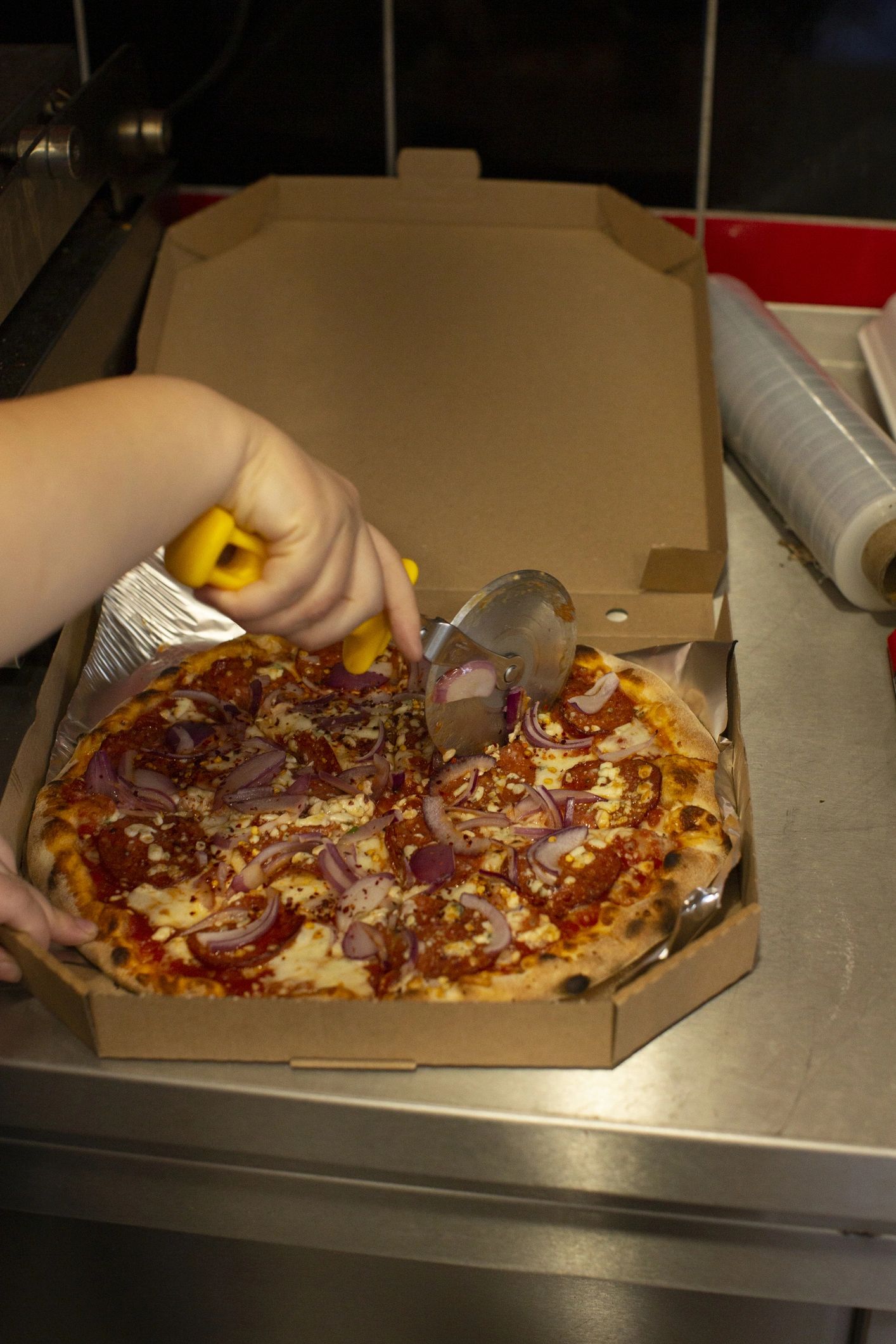 Chef hands preparing pizza, showing dough, sauce, and ingredients