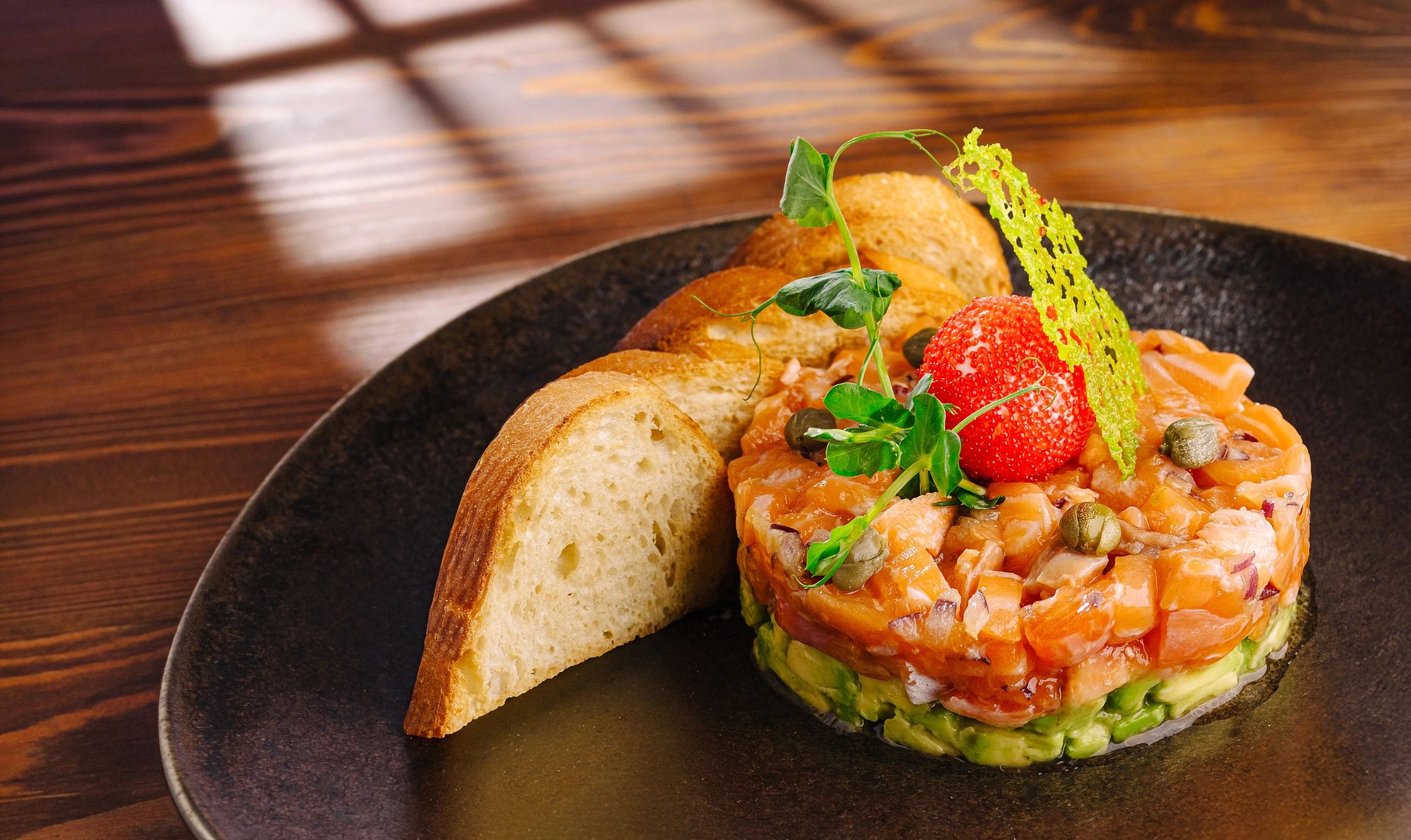 Salmon tartare plated with avocado and garnish